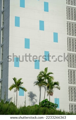 Building with concrete panel and masonry screen wall at Miami, Florida. There are plants and palm trees at the front of a multi-storey building.