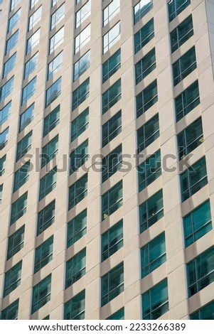 Grid multi-storey building close-up with clear reflective glass windows at Miami, Florida. Building exterior with square paned windows and a reflection of the sky at the above floors.