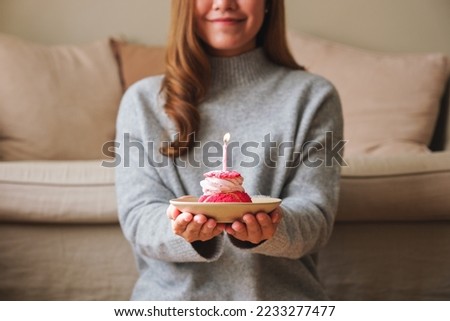 Closeup image of a young woman holding birthday cake with candle
