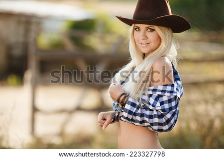 Young american cowgirl woman portrait outdoors. Beautiful natural woman saying hello looking at camera wearing cowboy hat. girl in her twenties outdoor in nature.