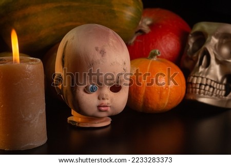 Yellow-orange pumpkins with broken cracked doll head candles and skulls on a black background the concept of Halloween and the autumn harvest of pumpkin close-up copyspace from above