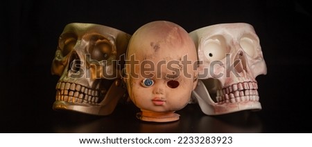 Damaged Dirty Doll head and skull on black background isolated