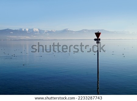 empty harbour of Lindau island on tranquil lake Constance or lake Bodensee with the Austrian Alps in the background on a fine winter evening with blue sky reflected in the water (Germany) Royalty-Free Stock Photo #2233287743