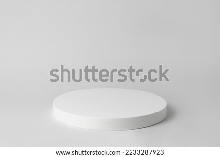 Empty white podium on light grey background. Minimal template. Round showcase for cosmetic product advertising. Abstract display or showcase. Spa and beauty mockup. Front view. Copy space.