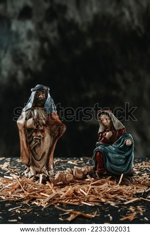 closeup of a depiction of the holy family, of saint joseph, the virgin mary and the child jesus, on the straw, against a dark background
