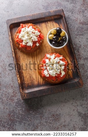 Dakos Cretan Meze appetizer with barley rusk, tomatoes, feta cheese, oregano and olive oil closeup on the wooden board on the table. Vertical top view from above
 Royalty-Free Stock Photo #2233316257