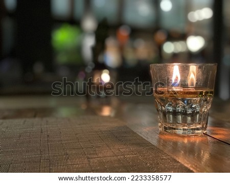 A candle placed on a light brown wooden table at night in a cafe