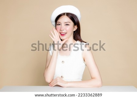 Cute Asian woman with perfect skin and screaming announcement. Pretty girl model wearing white beret and natural makeup on beige background. Cosmetology, beauty and spa, wellness, Plastic surgery.