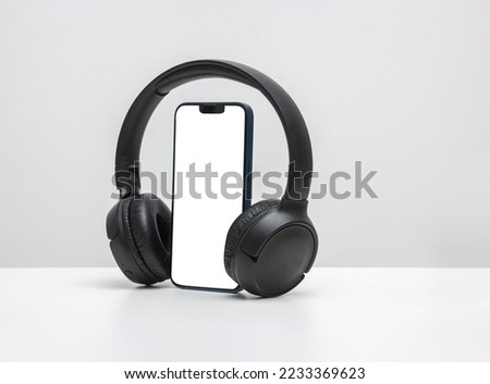 Smartphone with bluetooth headphones with white screen on blue neon background, for mockup and logo
