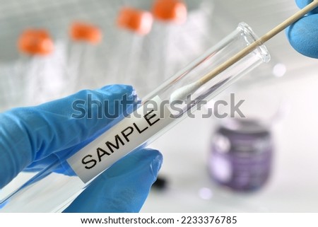 Nasal or oral swab being inserted test tube labeled sample for testing.