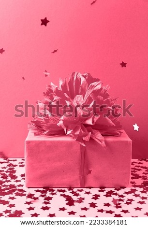 Gift box and falling confetti in trending Color of the Year 2023. Viva Magenta. Copy space for your design. Vertical photo. The concept of a holiday, invitations, sales, invitations to birthday