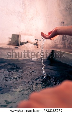 Child's hand playing with water in urban swimming pool, summer distraction, take care of natural resources, do not waste water.
