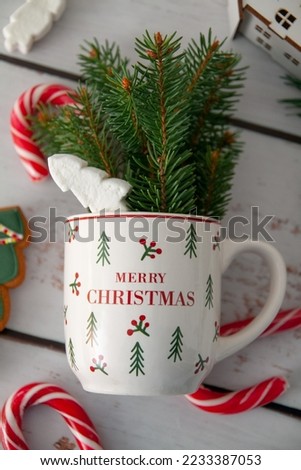 A cup with fir branches, marshmallows and candies nearby. Happy festive mood for 2022 and 2023