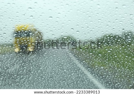 Blurred view of country road through wet car window. Rainy weather