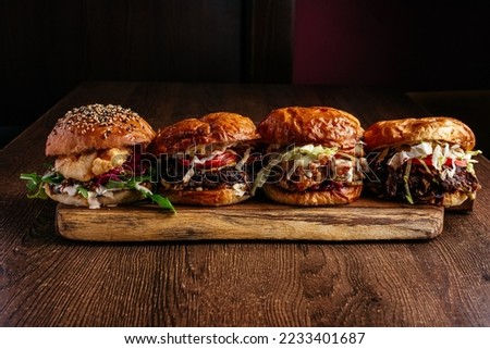 4 types of burgers on a wooden board