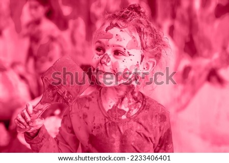 Pantone color 2023 viva magenta. Happy child girl hold paintbrush durty in the paint and all face stained with paint