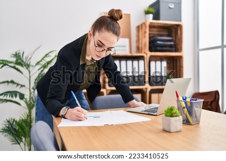 Young woman business worker writing on document at office