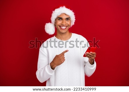 Photo of positive handsome guy beaming smile direct finger cellphone isolated on red color background