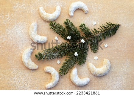 Vanilla rolls with nuts - delicious Christmas cookies, homemade baking. Romantic concept with sugared background, spruce twig and small sugar snowflakes