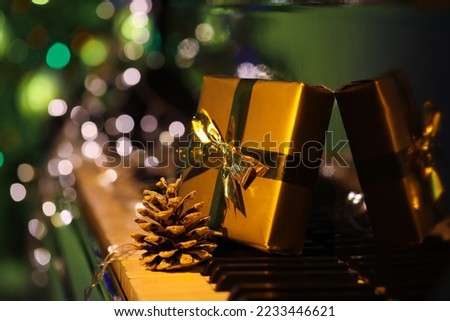 Christmas gift, pine cone and glowing lights on black piano, closeup