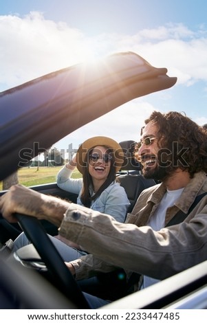 Vertical A young Caucasian couple driving in a convertible car. A cheerful boyfriend with his pretty bride travel in a vehicle enjoying the freedom of a weekend trip. Smiling people having fun Royalty-Free Stock Photo #2233447485