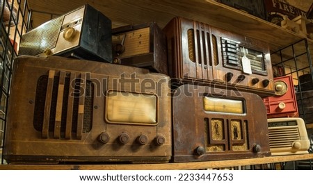 A variety of vintage table top radios grouped together on a shelf indoors closeup view Royalty-Free Stock Photo #2233447653