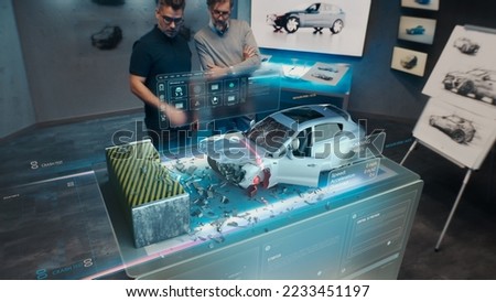 Two engineers Developers standing in design studio near futuristic holographic table and make a test in a 3d car crash test simulator, which simulates a road accident check the safety Royalty-Free Stock Photo #2233451197