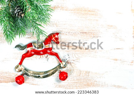vintage christmas decoration rocking horse with pine branch over wooden background. selective focus. toned picture