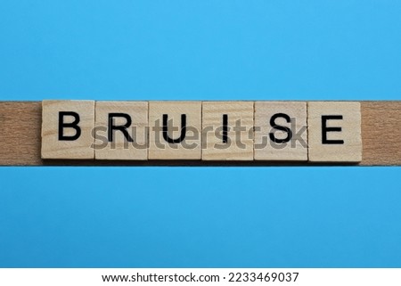 word bruise made from wooden gray letters lies on a blue background