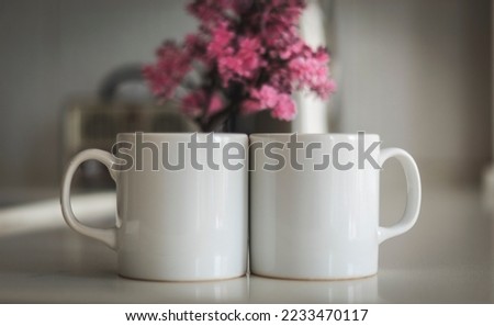 Two mug mockup on kitchen counter. Sublimation white blank two mug mock up for e-commerce sellers and designers and a beautiful pink flower in the background to increase sales