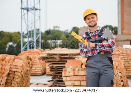 construction mason worker bricklayer installing red brick with trowel putty knife outdoors Royalty-Free Stock Photo #2233474917