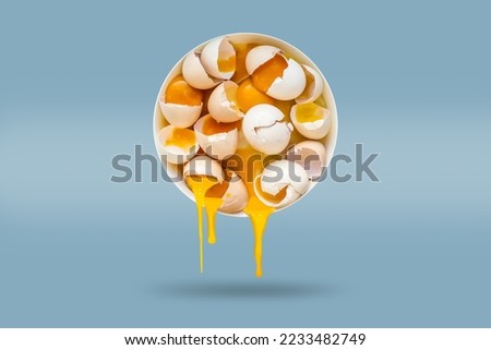 Broken eggs with shells in a round plate in the air on a blue background. Weightlessness concept, food in the air, zero gravity.