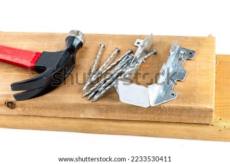 A galvanized steel rafter or joist hanger with hammer and nails as be used in residential construction Royalty-Free Stock Photo #2233530411