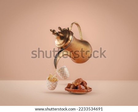 dallah is a metal pot with a long spout designed specifically for making Arabic coffee, Saudi coffee wood background, arabic coffee and dates. Royalty-Free Stock Photo #2233534691