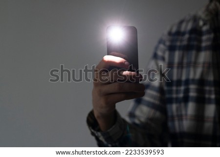 hand holding a smartphone used as a torched, flashlight of mobile phone in the dark