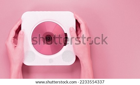 Color of year 2023 Viva Magenta. Image with hands holding stylish portable compact CD player with disc is toned in pantone color. New Fashion colour. Retro vintage player. Top view, space for text