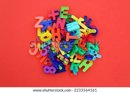 There are many different bright multi-colored letters and numbers on a red background.