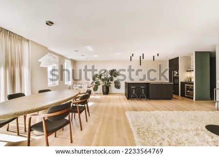 Contemporary minimalist style interior design of light studio apartment with wooden table and chairs in dining zone between open kitchen and living room with white walls and parquet floor Royalty-Free Stock Photo #2233564769