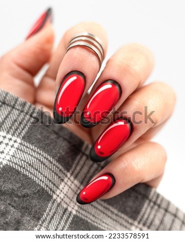 Close up woman's hand with red matt almond shaped nails, with black and white details.
