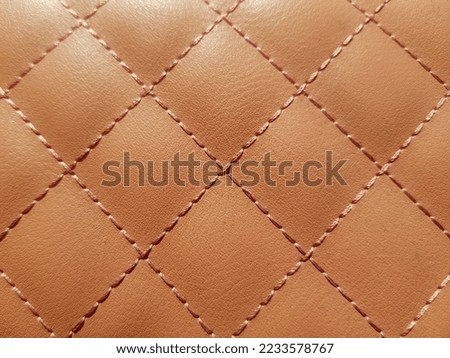 Brown imitation leather with a small grainy print and a geometric print of squares, in the sun (macro, top view, texture).
 Royalty-Free Stock Photo #2233578767