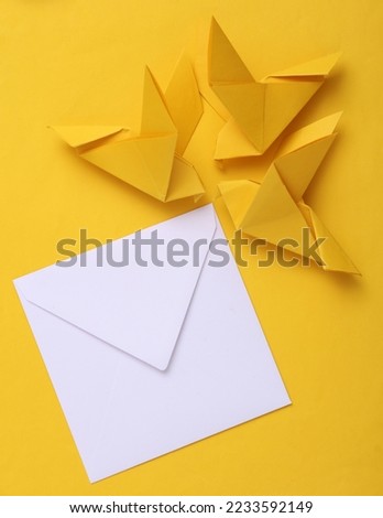 Origami carrier pigeons with a white envelope on yellow background
