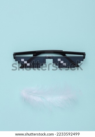 Pixel sunglasses with a feather on a blue background. Creative layout