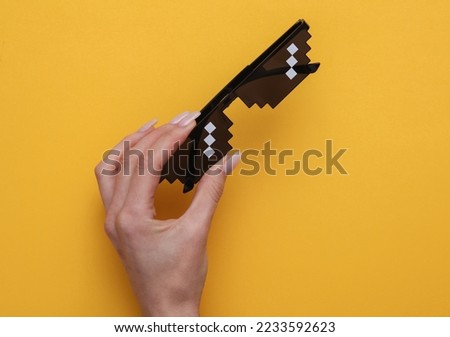Woman's hand holding pixel glasses on yellow background