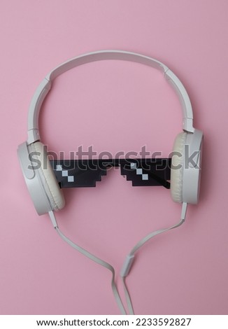 Stereo headphones with Pixelated 8 bit sunglasses on pink pastel background