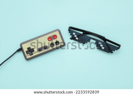 Pixelated 8 bit sunglasses with gamepad on pastel background
