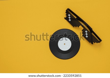 Stereo headphones with vinyl record on yellow background. Music concept