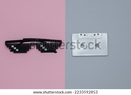 Pixelated 8 bit sunglasses with audio cassette on pastel background