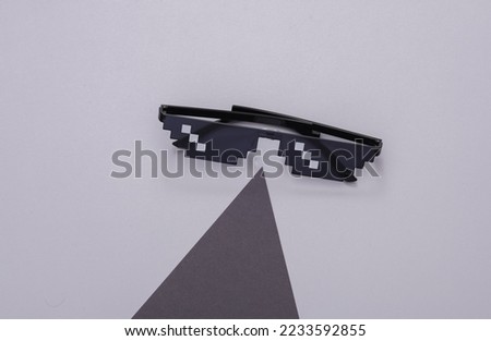 Pixelated 8 bit sunglasses on a gray background