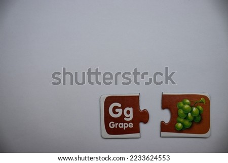 Grape picture puzzle pieces in red, white and green, placed separately from each other, to the lower right