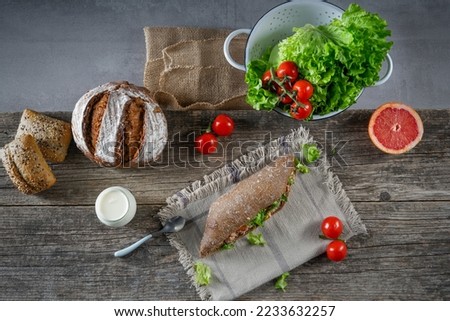 Tuna sandwich with letuce and tomato on woden table, fruits and vegetables. Colorful fresh group of vegetables and fruits. The concept of healthy eating.
